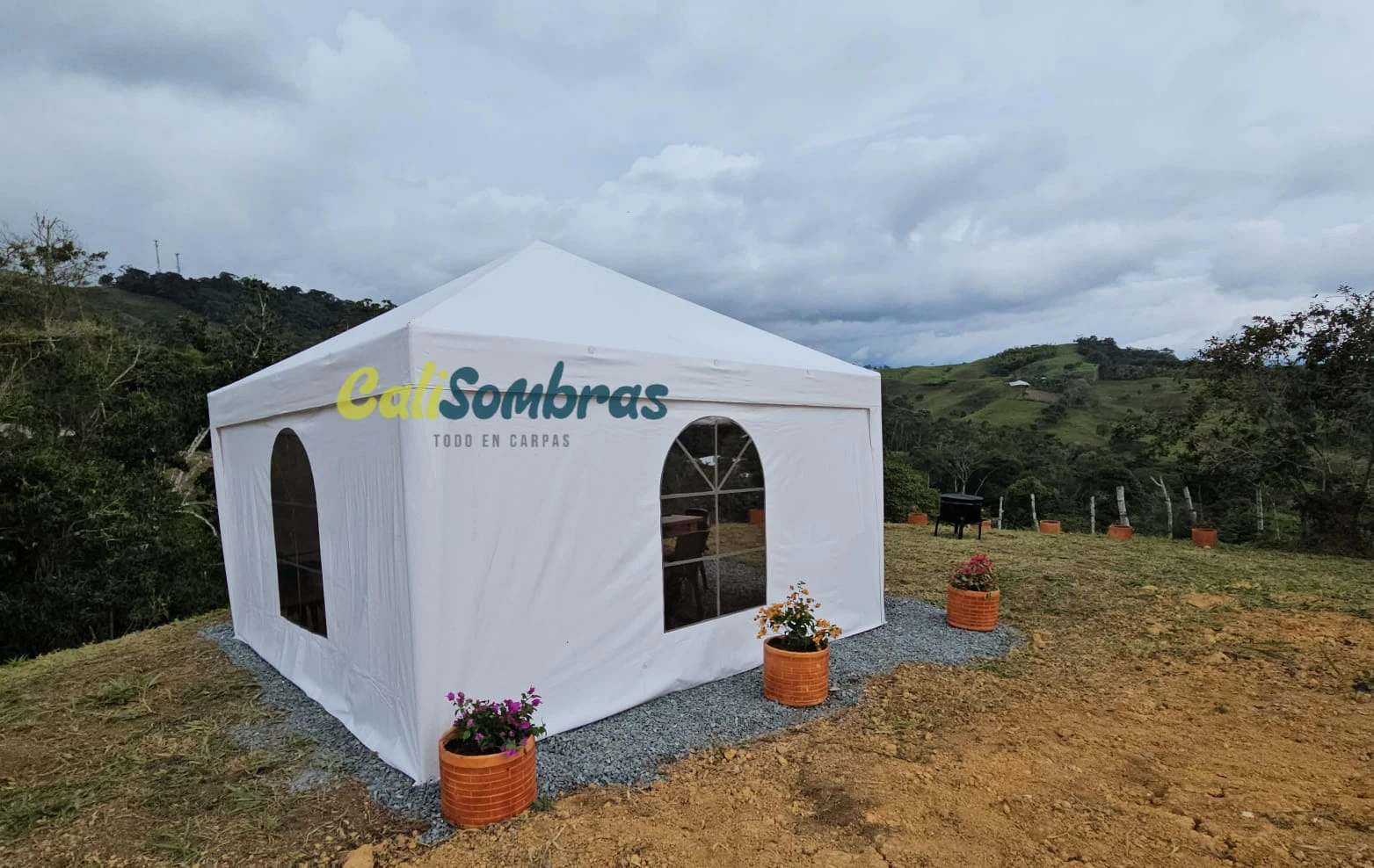 Carpa blanca con paredes y ventanas instalada en finca campestre